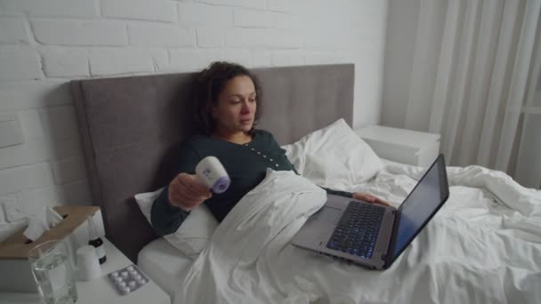 Хвора жінка, яка приймає медичну консультацію через відеодзвінок на ноутбуці в приміщенні — стокове відео