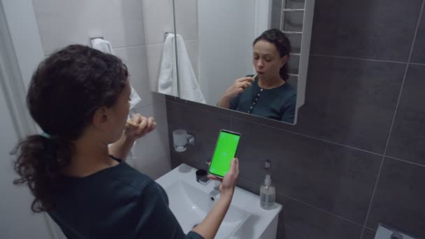 Černá žena při pohledu na smartphone s klíčem chroma při čištění zubů — Stock video