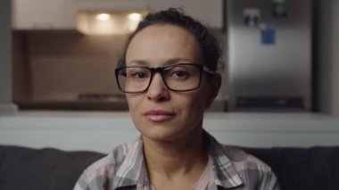 Çekici bir kadın, gözlüklerini indiriyor, evde dalgın dalgın bakıyor.