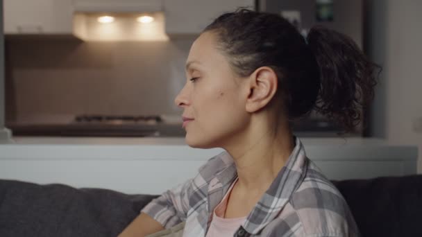 Confident adult female having pensive look, sitting on couch indoors — Wideo stockowe