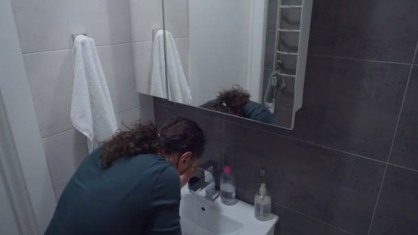 Віддзеркалення дорослої жінки в піжамі, що миє обличчя у ванній — стокове відео