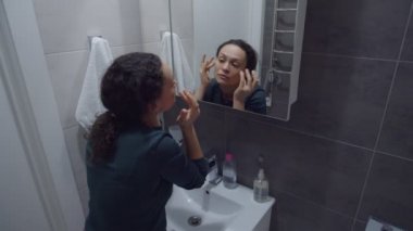 Büyüleyici yetişkin kadın. Yüzünde kırışıklık ve sivilce var mı diye kontrol ediyor.