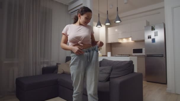 Erwachsene Frau freut sich über erfolgreiche Gewichtsabnahme und bewundert ihren Körper im Haus — Stockvideo