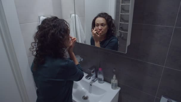 Confident adult woman applying cream, moisturizing face skin indoors — Stockvideo