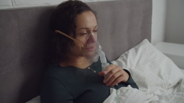 Sick woman inhaling vapor medication via nebulizer inhaler face indoor — Stockvideo