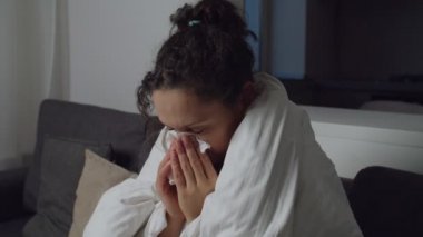 Sick adult woman coughing, blowing nose, using nasal spray indoors