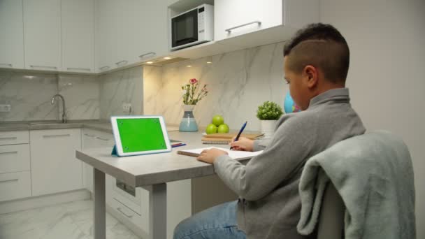 Back view of school boy doing schoolwork online via tablet indoors — Stock Video