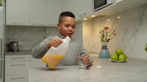 Knappe zwarte jongen gieten glas sap, drinken het binnen — Stockvideo