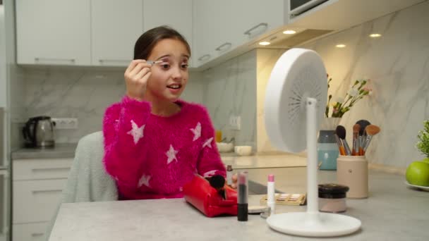 Adorable niña preadolescente aplicando maquillaje, admirando su reflejo en el interior — Vídeo de stock