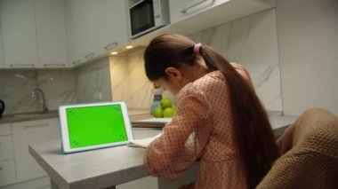 Evde tablet kullanarak ödev yapan liseli bir kızın dikiz görüntüsü