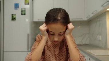 Kafası sallanan, üzgün, evde kaşlarını çatan, üzgün ergen bir kız.
