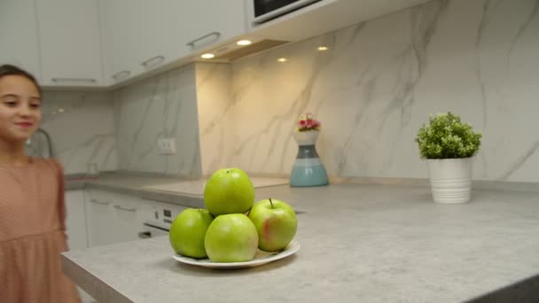 Preteen menina tomando frutas, mordendo maçã, sorrindo charmingly indoor — Vídeo de Stock