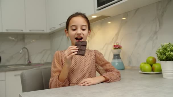 Güzel kız bütün çikolatayı yiyor, evde tatlının tadını çıkarıyor. — Stok video