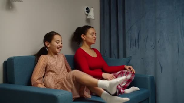 Calma madre y preadolescente chica sentado en la pose de loto en el sofá juntos — Vídeos de Stock