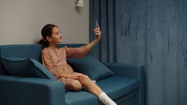 Chica preadolescente tomando selfie usando teléfono móvil, mensajería de fotos en el interior — Vídeos de Stock