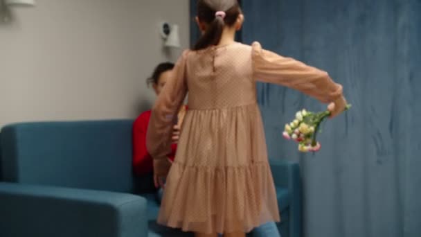 Chica preadolescente felicitando a madre multiétnica con flores en casa — Vídeos de Stock