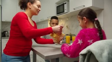 Evde kahvaltı yapan iki çocuklu mutlu bir aile.