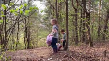 Anaokulu çocukları ellerinde plastik çöplerle dolu bir torba tutuyorlar.