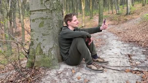 Jovem usando telefone inteligente na bela natureza — Vídeo de Stock