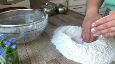 Tanımlanamayan kadın elleri içeride hamur yoğurmaya un hazırlıyor.