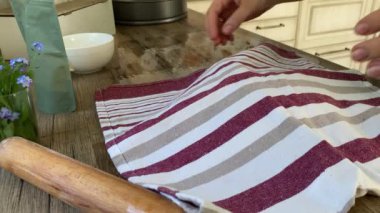 Kadın ev mutfağında hamurdan bulaşık havlusunu çıkarıyor.