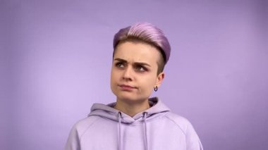 Tarz sahibi genç bir kadın düşünceli bir görünüm takınıyor. Mor renkli arka plan. Havalı kadın bireyselliği modaya uygun kapüşonlu giyer, düşünür, fikir edinir, çözümle sevinir. Tek Renkli