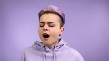 Havalı, şık, genç bir kadın. Gözleri kapalı. Esniyor, tek renk arka planda titriyor. Kapalı alanda tezahürat yapan mor kapüşonlu kadın hippi kısa menekşe saçlarının ayrı bir portresi. Tek Renkli