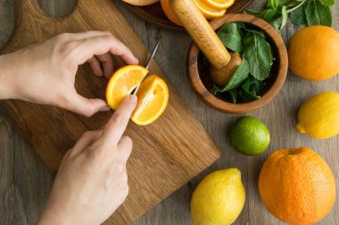 Tahta tahtada turuncu parçaları kesen kadınların masa manzarası. Taze narenciye tatlı yiyecekler hazırlıyorlar. Katı portakal, limon, greyfurt, kireç ve kabuklu harç, etrafta nane şekeri