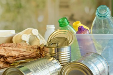 Yakın plan plastik şişeler, atık kağıtlar, bulanık arka planda teneke kutular. Plastik, kağıt, metal, geri dönüşüm, yükseltme, indirme gibi şeyleri ayırıyorum. Çevre koruma. Atık azaltılıyor