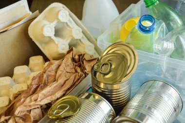 Yüksek açılı plastik şişe yığını, çöp kağıdı, bulanık arka planda teneke kutular. Plastik, kağıt, metal, geri dönüşüm ve geri dönüşüm için ayıklama malzemesi topluyoruz. Çevre koruma. Atık azaltılıyor