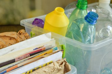 Naylon ayıklama, geri dönüşüm için kâğıt toplama, yükseltme, indirme. Konteynırlar farklı plastik şişeler ve bulanık arka plandaki atık kağıtları doldurdu. Çevre koruma. Atık azaltılıyor
