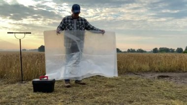 Toprağın verimli analizi için zemine yayılan tarımcı şafakta tahıl tarlasının arka planında toprak araştırmasına hazırlanıyor. Agronomi uzmanı sabah saha çalışması yapıyor. Toprak sertifika