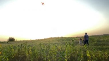 Father two kids flying kite on meadow at golden lights of sunset. Family two children having leisure on nature. Male parent, little girl, boy having fun together outdoors. Happiness in Simple living