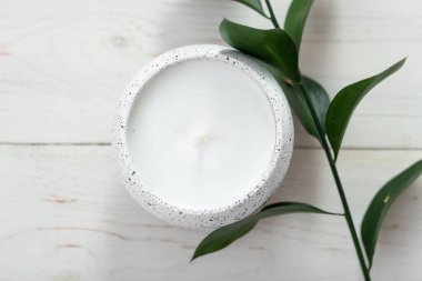 Bir mum ve beyaz bir masanın üzerinde bir bitki dalıyla kompozisyon. İç mekan. Metin için boşluk.