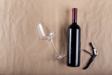 Kahverengi arka planda şarap şişesi, cam ve tirbuşon. Mesaj için yer var. Üst görünüm.