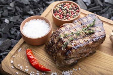 Ahşap bir masada ızgara biftek, ot ve baharat. Üst Manzara. Metnin için boş yer.