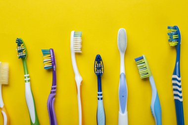 Sarı arka planda diş fırçaları. Ağız boşluğunda hijyen. Üst görünüm.