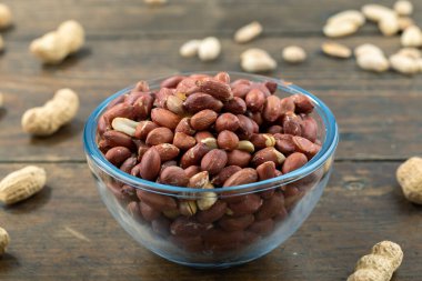 Cam bir kasenin içindeki kabuklarındaki fıstıklar ve derilerindeki fıstıklar masaya saçılmış. Mesaj için yer var. Yakın çekim..