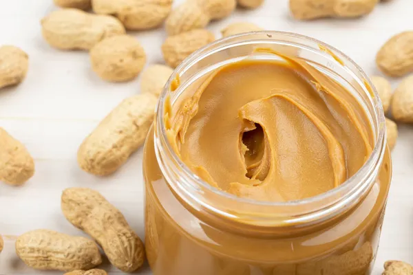Frasco Manteiga Amendoim Uma Mesa Madeira Branca Com Amendoins Espalhados — Fotografia de Stock