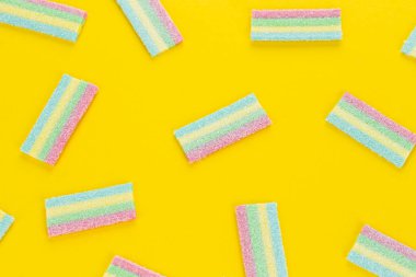 Sarı arka planda renkli şekerleme deseni. Yumuşak diş etleri yukarıdan görünüyor. Çeşitlilik konsepti. Eşcinsel renkleri. Tatlı yemek tatlısı. Yukarıdan görüntüle