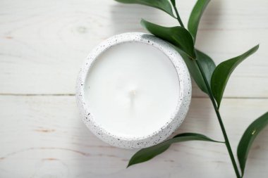 Bir mum ve beyaz bir masanın üzerinde bir bitki dalıyla kompozisyon. İç mekan. Metin için boşluk.