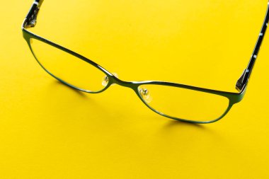 Stylish eyeglasses over yellow background. Glasses selection, eye test, vision examination at optician, fashion accessories concept. Top view, flat lay. Space for text. clipart