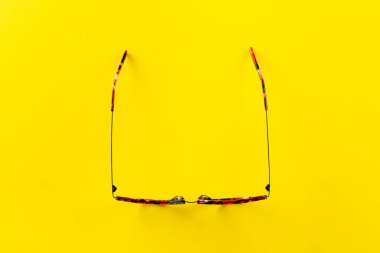 Sarı arka planda şık gözlükler. Gözlük seçimi, göz testi, göz doktorunda vizyon muayenesi moda aksesuarları konsepti. Üst manzara, düz yatış. Metin için boşluk.