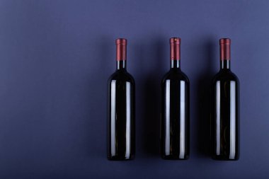 Mor kağıtta etiketi olmayan üç şişe kırmızı şarap. Etiketin ve mesajın yanında bir şeyler iç. Metin için boşluk.