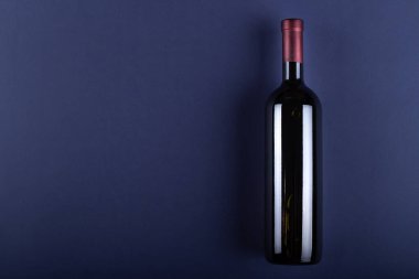 Mor kağıtta etiketi olmayan bir şişe kırmızı şarap. Etiketin ve mesajın yanında bir şeyler iç. Metin için boşluk. Üst görünüm.