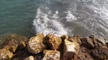 Güzel dalgalar ve Akdeniz taşlı sahilleri. Deniz dalgalarının çarpışma ve köpürme görüntülerinin yukarıdan aşağıya doğru görüntüsü. Taşların etrafında dönen dalgalara bakıyorum..