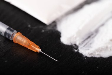 Kokain ya da diğer yasadışı uyuşturucular, beyaz toz, para, haplar, siyah arka planda şırınga. Seçici odak.