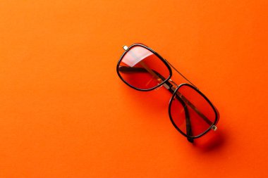 Turuncu arka planda siyah çerçeveli güneş gözlüğü. Şık aksesuarlar.