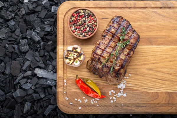Ahşap kesme tahtasında servis edilen baharatlı bir parça pişmiş biftek.
