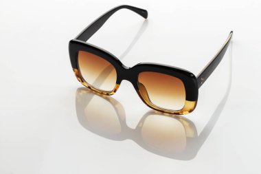 Beyaz yansıtıcı yüzeyde güneş gözlüğü. Modaya uygun, şık aksesuarlar. Tatil ya da yaz konsepti olarak kullan. Parlak güneş ışığına karşı göz koruması.